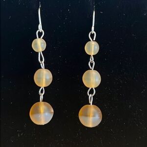 Handcrafted silver tone earrings with tan colored beads.